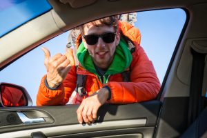 young male hitchhiker asking for a lift at the window of the car